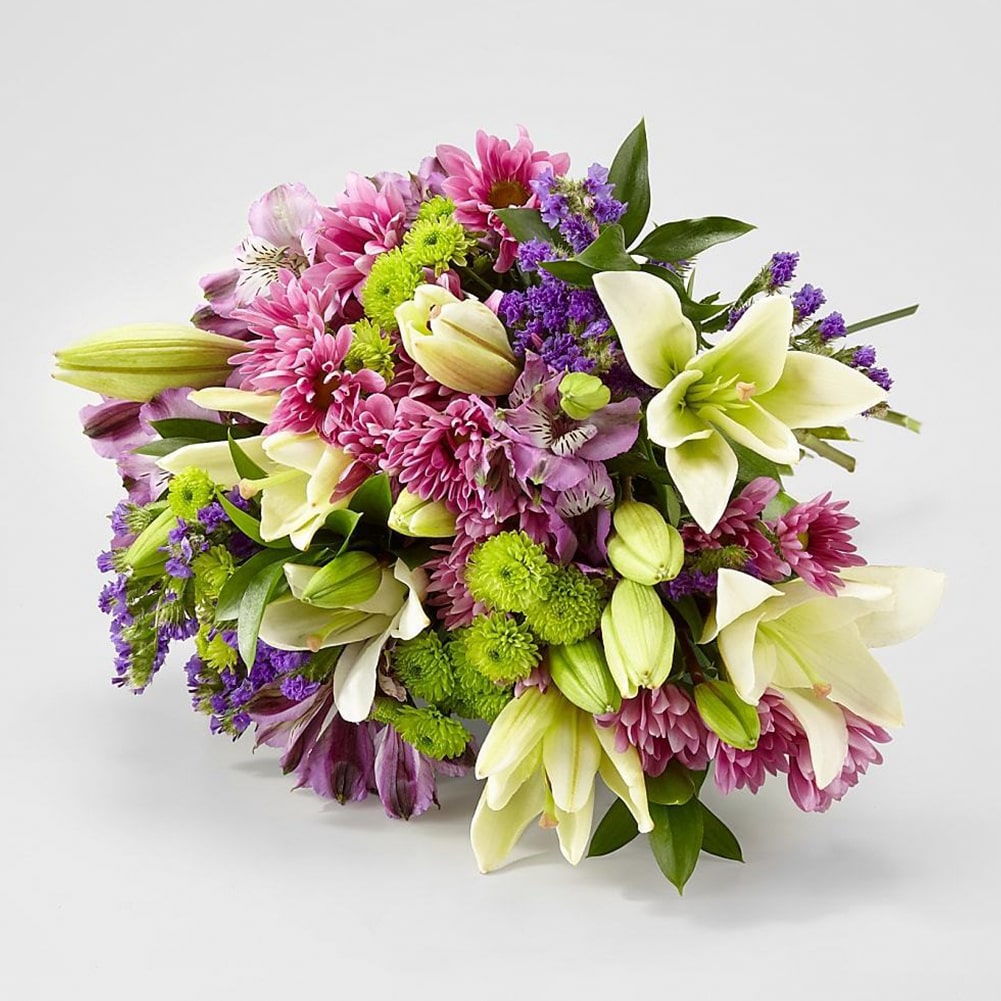 Lavender Fields Mixed Flower, white Asiatic Lilies, Purple Super Select Alstroemeria, Purple Button Pom, Lavender Daisy Pom, Purple Sinuata Statice, and an assortment of lush greens. Fresh Flowers Orlando.