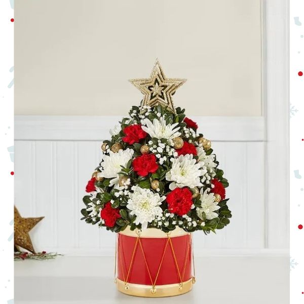 Árbol Musical de Flores Navideñas Small. En la última edición de nuestro clásico árbol de flores navideño, la alegría de hacer regalos cobra vida. Hemos añadido flores festivas, adornos dorados brillantes y una estrella en la parte superior. Detalles del arreglo: Rosas Rojas, Mini Claveles, Colores verdes navideños, Domicilio Gratis Orlando FL, Fresh Flowers Orlando.