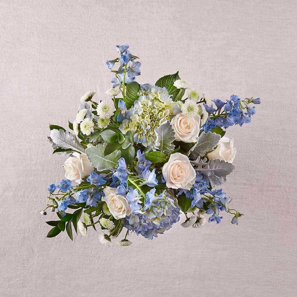 Cielos Abiertos (Symphaty Funeral Flowers), Arreglo de flores de condolencias para el hogar, elaborado con flores de hortensias y belladona delfinio que captura la sensación de un nuevo día, Fresh Flowers Orlando.