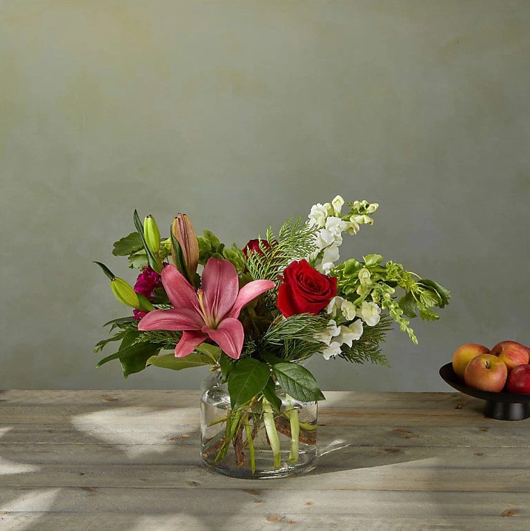 Ramo de Estrellas de Navidad Standard. Las Bocas de Dragón blancas y los Lirios híbridos junto con las Rosas, añaden un sutil cambio a la paleta navideña convencional en este ramo. Detalles del arreglo: Claveles, rosas, lirios, Campanas de Irlanda y Boca de Dragón, colores verdes navideños. Domicilio Gratis Orlando FL, Fresh Flowers Orlando.