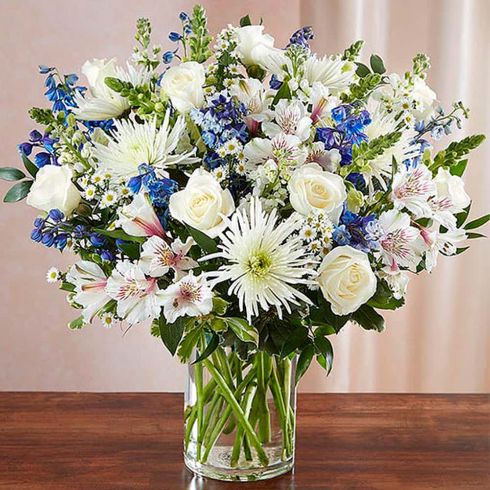 Sympathy Sincero Azul y Blanco, Size Large, Fresh Flowers Orlando. Our bountiful, heavenly blue and white bouquet features a soothing mix of blue delphinium, alstroemeria, and white roses, hand-designed inside a classic clear glass vase. When sent to a service or to the home of family or friends, it makes a genuinely heartwarming gesture. Nuestro ramo de flores en azul y blanco presenta una relajante mezcla de blue delphinium, alstroemeria y rosas blancas.